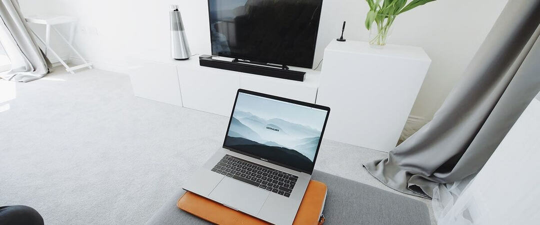 Laptop Mac pe pat cu televizor